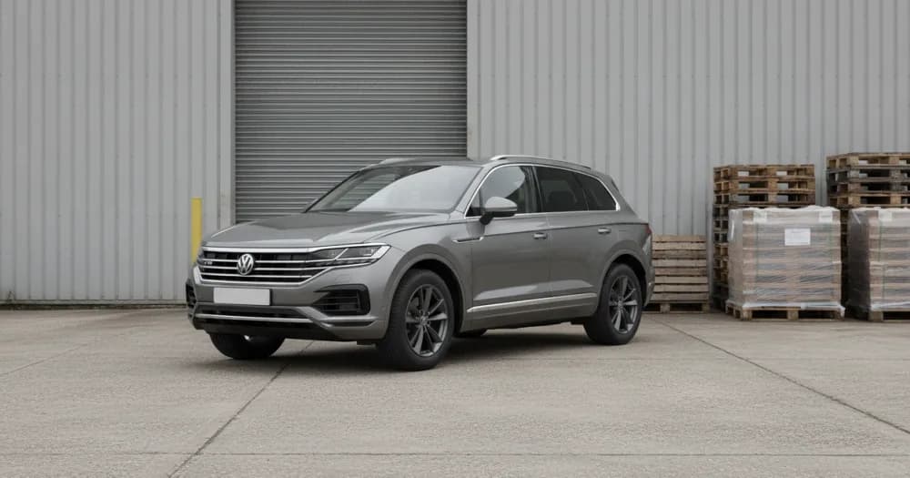 A silver Touareg parked at a warehouse loading bay, illustrating a volkswagen touareg lease cost. A silver Touareg parked at a warehouse loading bay, illustrating a volkswagen touareg lease cost.